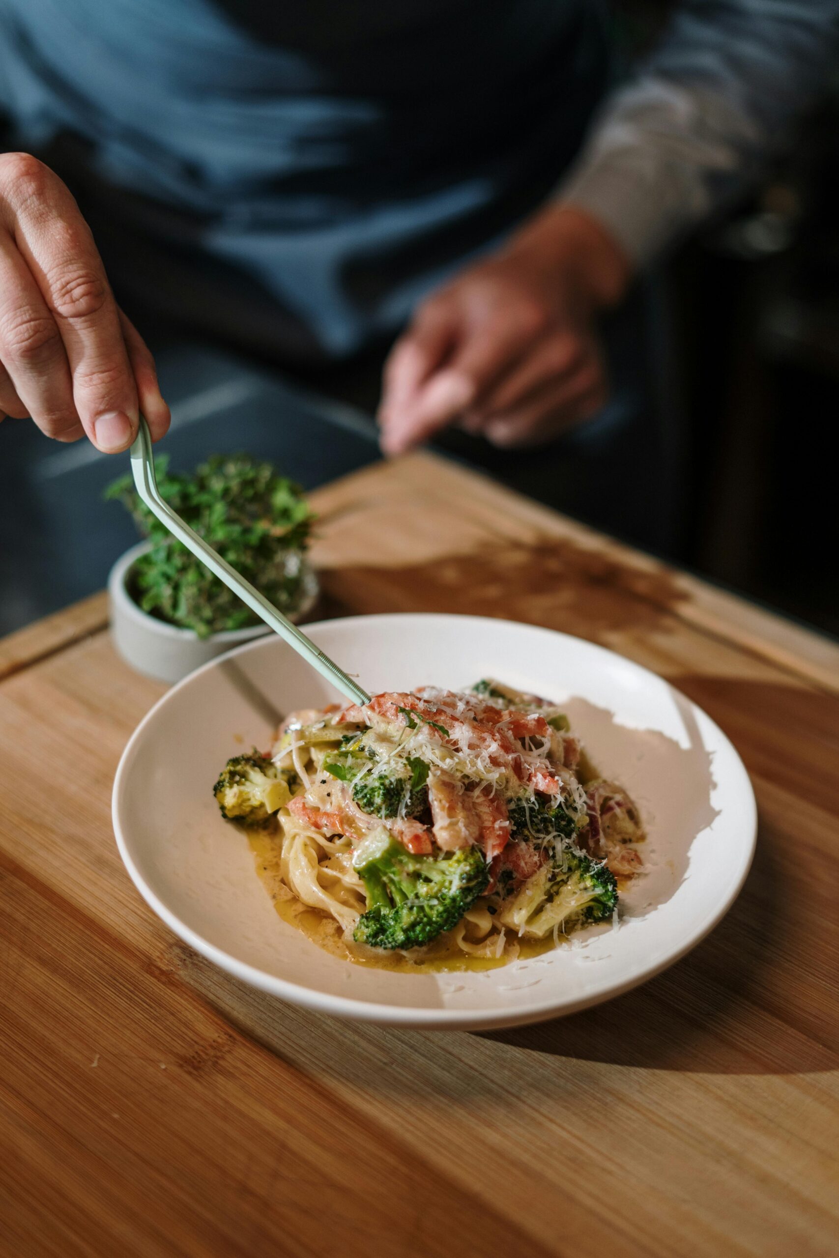 A delicious plate of Italian pasta garnished with fresh herbs and broccoli, prepared by a male chef.